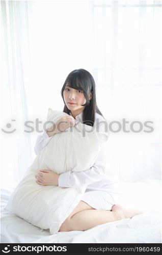 Portrait beautiful asian girl sitting with pillow at white bedroom