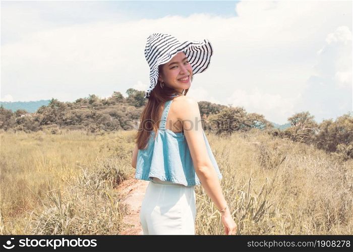 Portrait beautiful asian woman wearing hat and traveling in summer time with background of blur mountains and blue sky