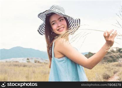 Portrait beautiful asian woman wearing hat and traveling in summer time with background of blur mountains and blue sky