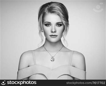 Portrait Beautiful Blonde Woman with Jewelry. Model Girl in Elegant White Dress. Magnificent Hairstyle. Precious Stones and Silver. Beauty and Fashion Accessories. Perfect Make-Up. Black and White photo