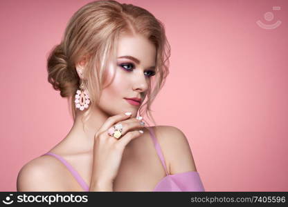 Portrait Beautiful Blonde Woman with Jewelry. Model Girl with Pearl Manicure on Nails. Elegant Hairstyle. Precious Stones and Silver. Beauty and Fashion Accessories. Perfect Make-Up. Pink Background