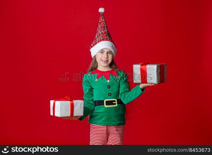 Portrait beautiful elven baby. Elf girl with gifts, Santa Claus helper on a bright red bright colored background. Copy space.. Elf girl with gifts, Santa Claus helper on a bright red bright colored background. Portrait beautiful elven baby.