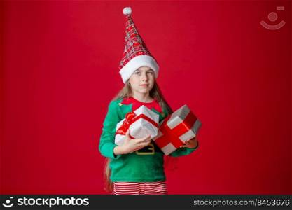 Portrait beautiful elven baby. Elf girl with gifts, Santa Claus helper on a bright red bright colored background. Copy space.. Elf girl with gifts, Santa Claus helper on a bright red bright colored background. Portrait beautiful elven baby.