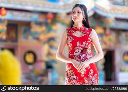 Portrait beautiful smiles Asian young woman wearing red cheongsam dress traditional decoration for Chinese new year festival celebrate culture of china at Chinese shrine in Thailand