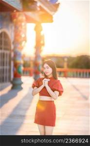 Portrait beautiful smiles Asian young woman wearing red cheongsam dress traditional decoration for Chinese new year festival celebrate culture of china at Chinese shrine Public places in Thailand