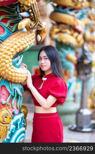 Portrait beautiful smiles Asian young woman wearing red cheongsam dress traditional decoration for Chinese new year festival celebrate culture of china at Chinese shrine Public places in Thailand