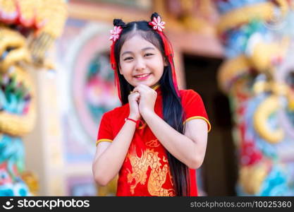 Portrait beautiful smiles Cute little Asian girl wearing red traditional Chinese cheongsam decoration for Chinese New Year Festival at Chinese shrine