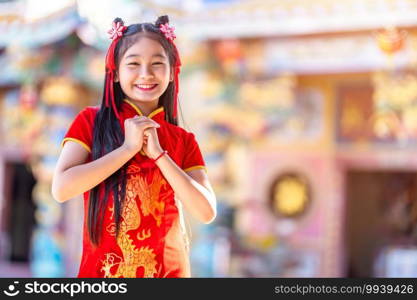 Portrait beautiful smiles Cute little Asian girl wearing red traditional Chinese cheongsam decoration for Chinese New Year Festival at Chinese shrine