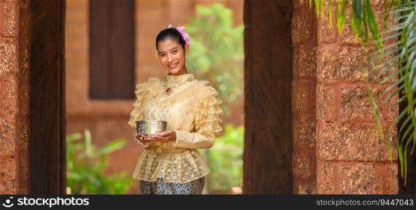 Portrait beautiful woman in Songkran festival with Thai Traditional costume in the temple holding water bowl and smile. Thailand culture with Water festival