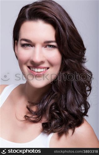Portrait beautiful woman with dark hair smiling in the camera. Portrait beautiful woman with dark hair smiling in the camera on grey background