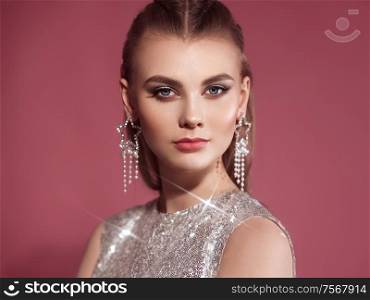 Portrait beautiful woman with jewelry. Brunette girl with long smooth hair. Beauty fashion. Eyelashes. Cosmetic eyeshadow. Care and beauty hair products. Model in a silver dress