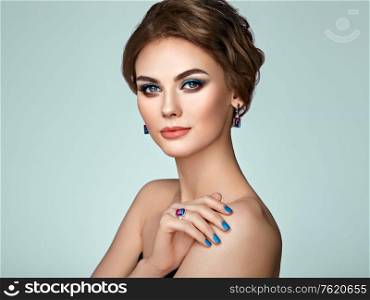 Portrait beautiful woman with jewelry. Model girl with blue manicure on nails. Beauty and Accessories. Pink lipstick