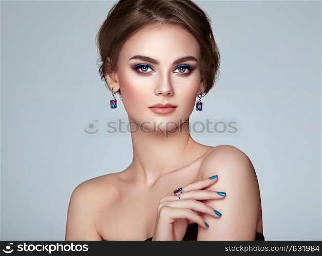 Portrait beautiful woman with jewelry. Model girl with blue manicure on nails. Beauty and Accessories. Pink lipstick