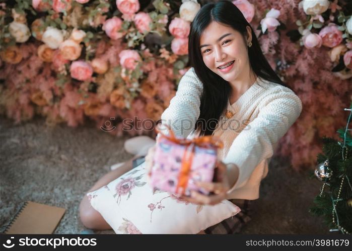 Portrait beautiful young asian woman girl wearing warm clothes exchanging gifts and Give a present at house home in the living room inside or cafe,During Christmas x-mas and New Year holidays.