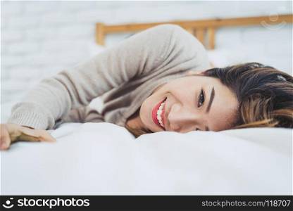 Portrait beautiful young Asian woman on bed at home in the morni. Portrait beautiful young Asian woman on bed at home in the morning. Cheerful Asian woman wearing a comfortable sweater and smiling on her bed. Relaxing room. lifestyle asia woman at home concept.