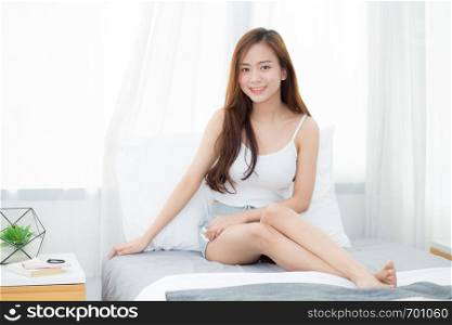 Portrait beautiful young asian woman sitting and smile the window at bedroom while wake up with sunrise at morning, lifestyle and relax concept.