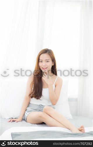 Portrait beautiful young asian woman sitting and smile the window at bedroom while wake up with sunrise at morning, lifestyle and relax concept.