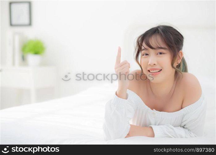Portrait beautiful young asian woman smile wake up healthy and wellness at morning, beauty asia girl lying and pointing something skin care and makeup cosmetic with happy, lifestyle and relax concept.