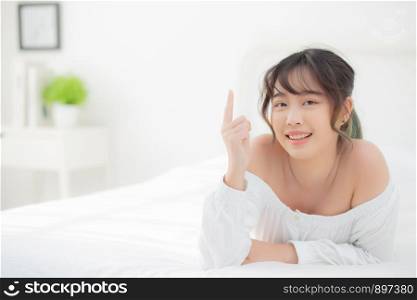 Portrait beautiful young asian woman smile wake up healthy and wellness at morning, beauty asia girl lying and pointing something skin care and makeup cosmetic with happy, lifestyle and relax concept.