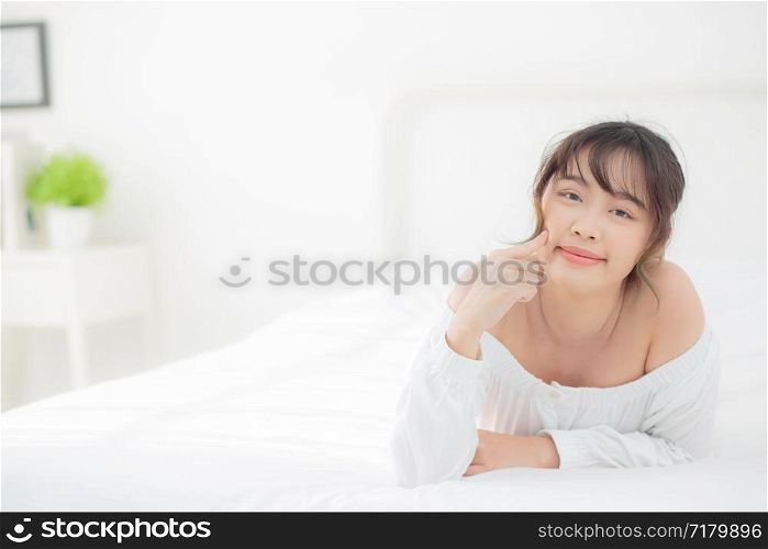 Portrait beautiful young asian woman smile while wake up healthy and wellness at morning in the bedroom, beauty asia girl lying skin care and makeup cosmetic with happy, lifestyle and relax concept.