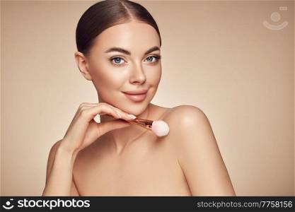 Portrait beautiful young woman with clean fresh skin. Model with cosmetic makeup brush. Cosmetology, beauty and spa