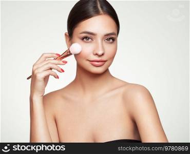 Portrait beautiful young woman with clean fresh skin. Model with cosmetic makeup brush. Healthy clean fresh skin natural make up beauty eyes