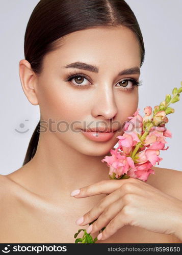 Portrait beautiful young woman with clean fresh skin. Model with healthy skin, close up portrait. Cosmetology, beauty and spa. Girl with a pink  flower