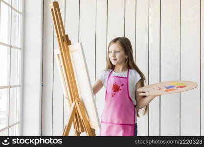 portrait blonde girl holding wooden palette painting easel