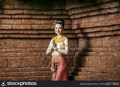 Portrait Charming Thai woman in Beautiful traditional dress costume, woman wearing typical thai dress in brick wall of archaeological site or thai temple background, identity culture of thailand