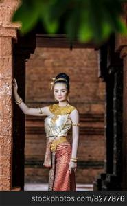 Portrait Charming Thai woman in Beautiful traditional dress costume, woman wearing typical thai dress standing in archaeological site or thai temple background, identity culture of thailand