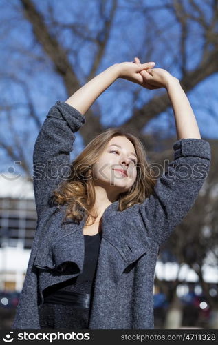 Portrait close up of young beautiful blonde schoolgirl on spring street background