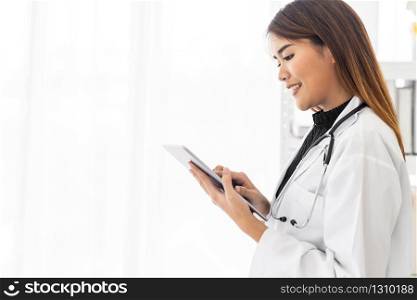 Portrait confident female doctor medical professional standing and use digital tablet in examination room in hospital clinic. Positive face expression