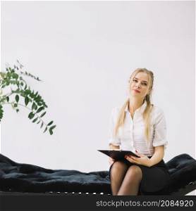 portrait confident female psychologist sitting couch holding clipboard