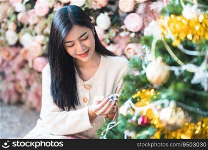 Portrait Cute beautiful positive smile young asian woman decorating to a Christmas tree at home in the living room indoors Decoration During Christmas x-mas and New Year holidays.