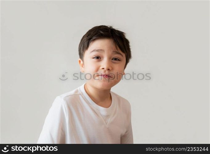 Portrait cute happy young boy wearing white T- shirt looking up with surprised face, Head shot Positive kid with smiling face and making funny face. Children days concept