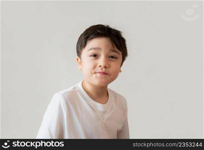 Portrait cute happy young boy wearing white T- shirt looking up with surprised face, Head shot Positive kid with smiling face and making funny face. Children days concept