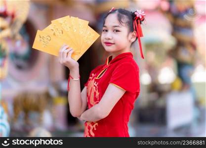 Portrait Cute little Asian girl wearing red traditional Chinese cheongsam decoration holding yellow envelopes with the Chinese text Blessings written on it Is a Good luck for Chinese New Year Festival