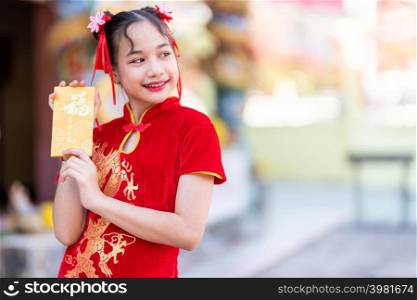 Portrait Cute little Asian girl wearing red traditional Chinese cheongsam decoration holding yellow envelopes with the Chinese text Blessings written on it Is a Good luck for Chinese New Year Festival
