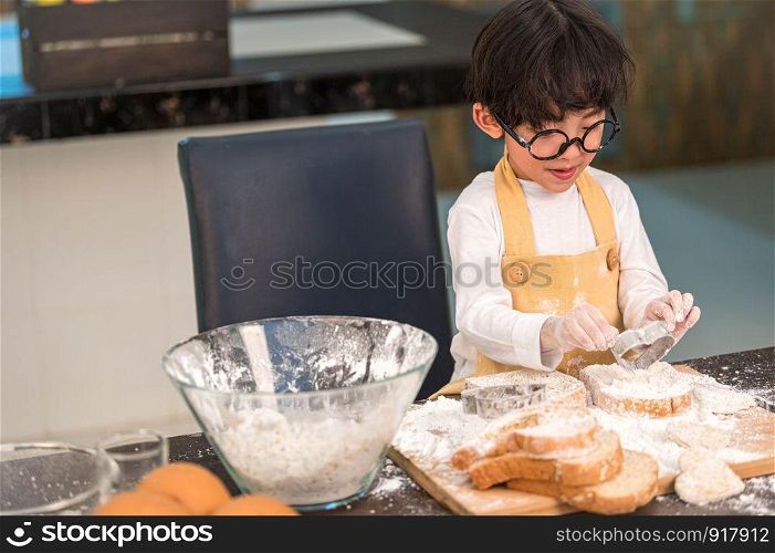 Portrait cute little Asian happiness boy interested in baking bakery with funny in home kitchen. People lifestyles and Family. Homemade food and ingredients concept. Baking Christmas cake and cookies