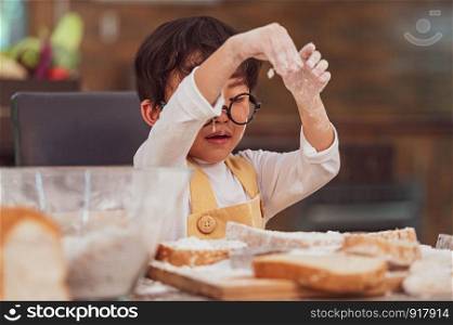 Portrait cute little Asian happiness boy interested in baking bakery with funny in home kitchen. People lifestyles and Family. Homemade food and ingredients concept. Baking Christmas cake and cookies