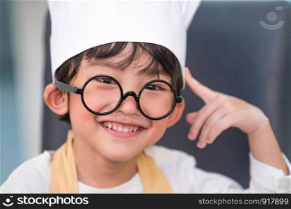 Portrait cute little Asian happiness boy interested in cooking with mother funny in home kitchen. People lifestyles and Family. Homemade food and ingredients concept. Baking Christmas cake and cookies