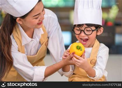 Portrait cute little Asian happy boy chef interested in cooking with mother funny in home kitchen. People lifestyles and Family. Homemade food and ingredient concept. Vegetable salad making