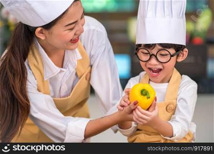 Portrait cute little Asian happy boy chef interested in cooking with mother funny in home kitchen. People lifestyles and Family. Homemade food and ingredient concept. Baking Christmas cake and cookies