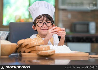 Portrait cute little Asian happy boy interested in cooking funny in home kitchen. People lifestyles and Family. Homemade food and ingredients concept. Baking Christmas cake and cookies. Smiling child