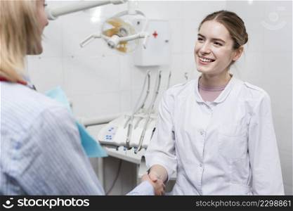 portrait dentist shaking hand with patient