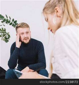 portrait depressed male patient talking with female psychologist