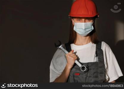 portrait female worker is wear protection mask face, safety helmet and suit and with big screw key, wrench in hands. For working industrial due to covid pandemic crisis concept. portrait female worker is wear protection mask face, safety helmet and suit and with big screw key, wrench in hands. For working industrial due to covid pandemic crisis concept.