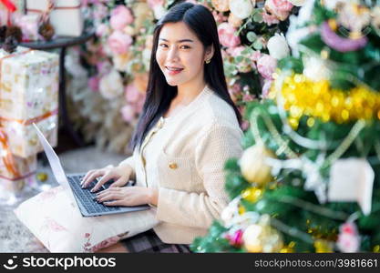 Portrait freelance business beautiful positive smile young asian woman online working with laptop computer at home in the living room indoors Decoration During Christmas x-mas and New Year holidays.