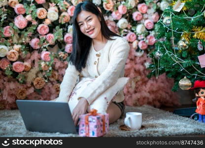 Portrait freelance business beautiful positive smile young asian woman online working with laptop computer at home in the living room indoors Decoration During Christmas x-mas and New Year holidays.