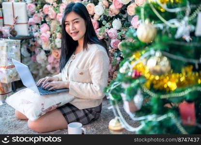 Portrait freelance business beautiful positive smile young asian woman online working with laptop computer at home in the living room indoors Decoration During Christmas x-mas and New Year holidays.